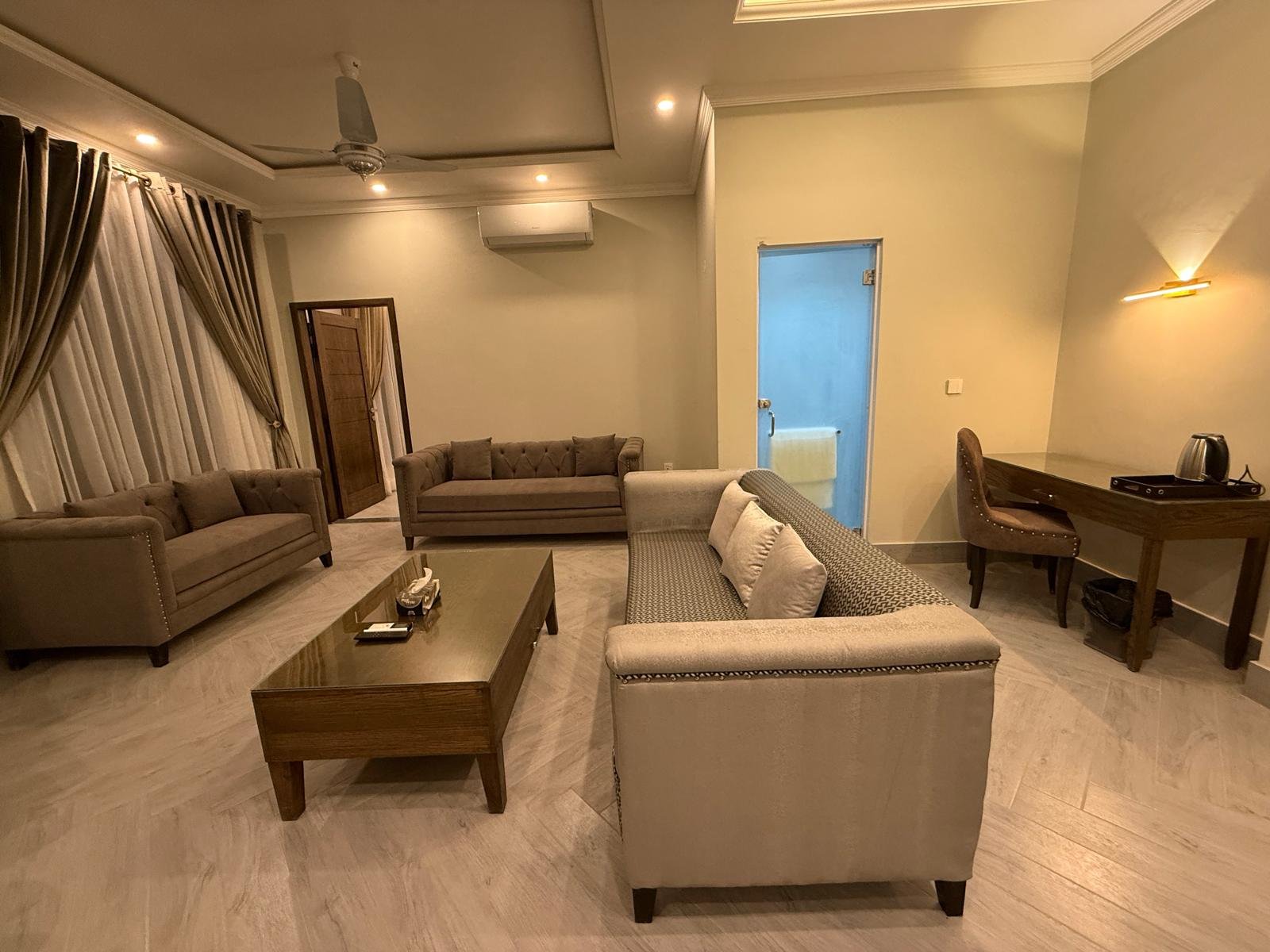 Suite sitting area with sofas and work desk at Regency Suites Lahore